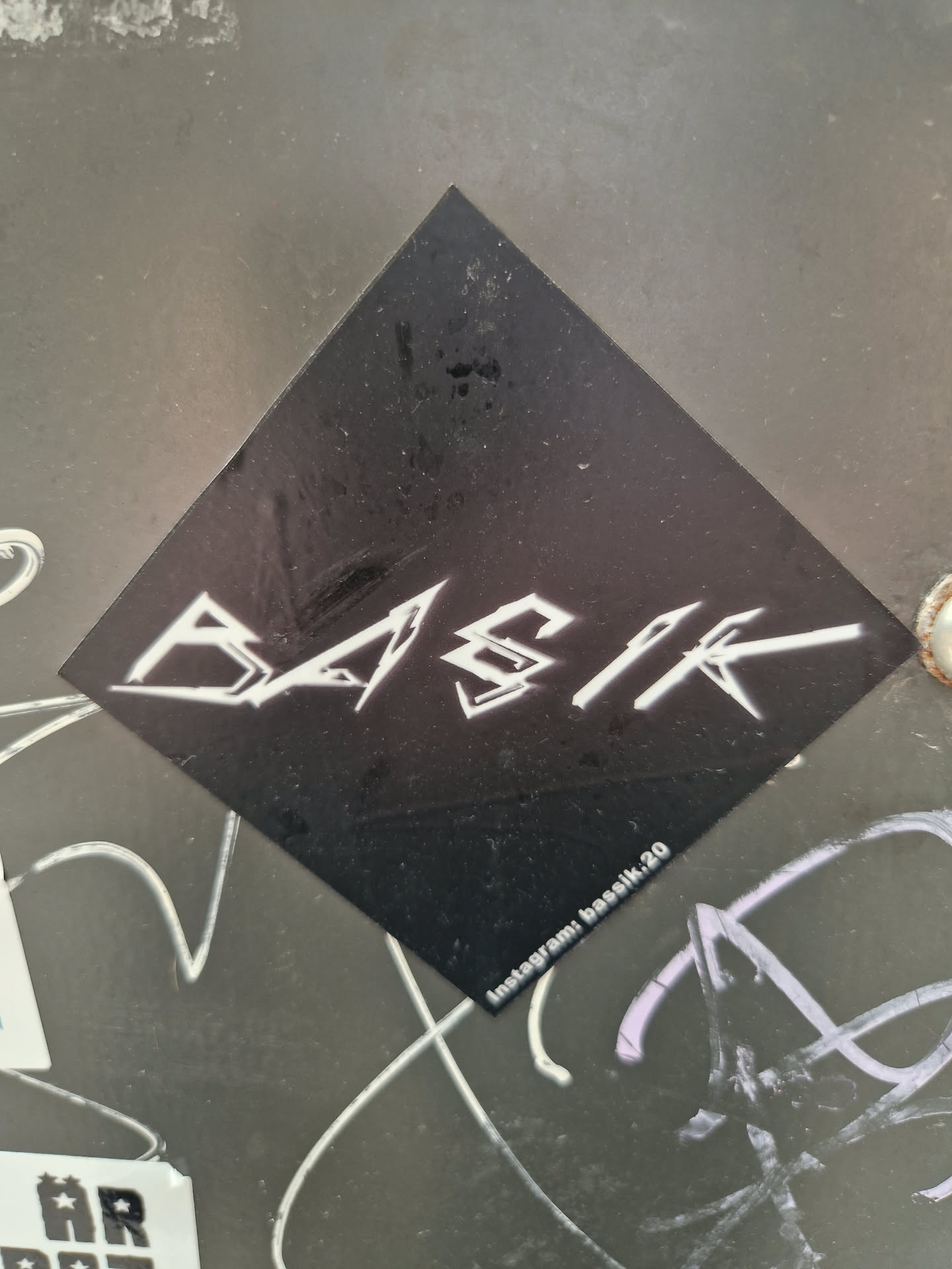 A black diamond-shaped sticker features a white stylized logo that appears to be the word 'BYSR'.  The Instagram handle 'basik.20' is printed at the bottom of the sticker.