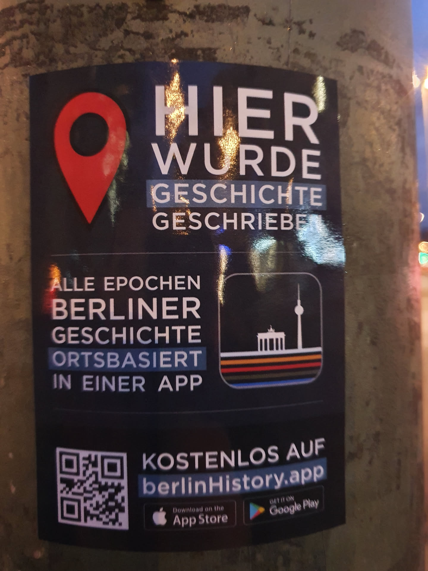 This sticker promotes the berlinHistory app, a location-based app that showcases the history of Berlin.  The text on the sticker says, "Here history was written." and it features a QR code linking to the app's download pages.