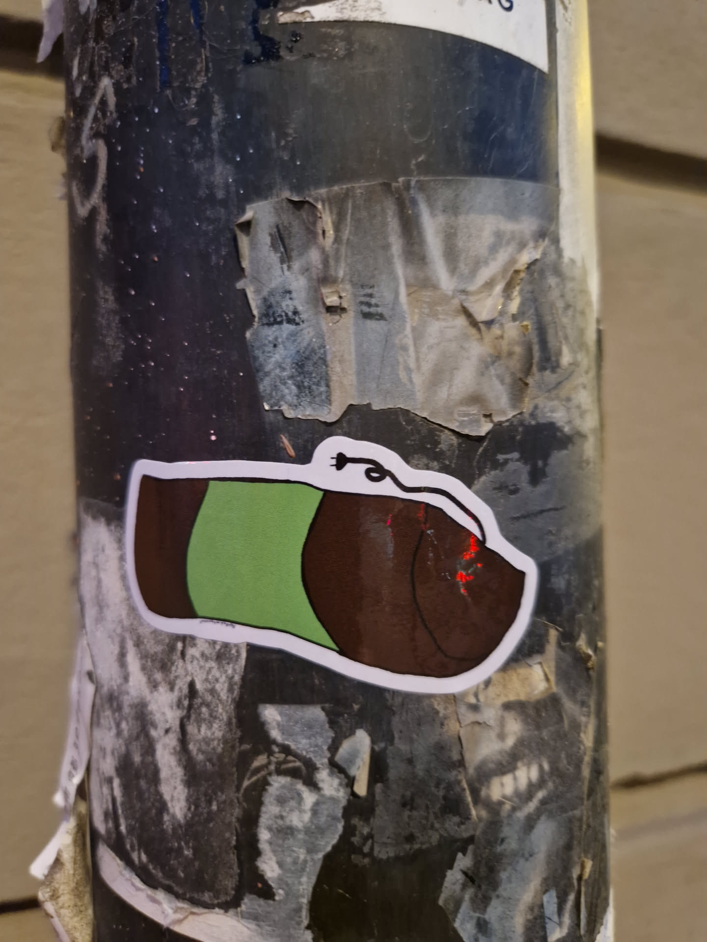 A sticker featuring a simple drawing of a sleeping bag in brown and green colors.  The style is minimalist and cartoonish.