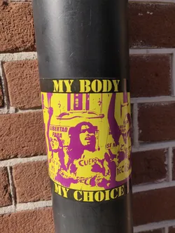 A sticker depicting a protest scene with women holding signs. The text on the sticker says "My Body, My Choice" in bold yellow letters on a black background. The image is stylized in purple and yellow.