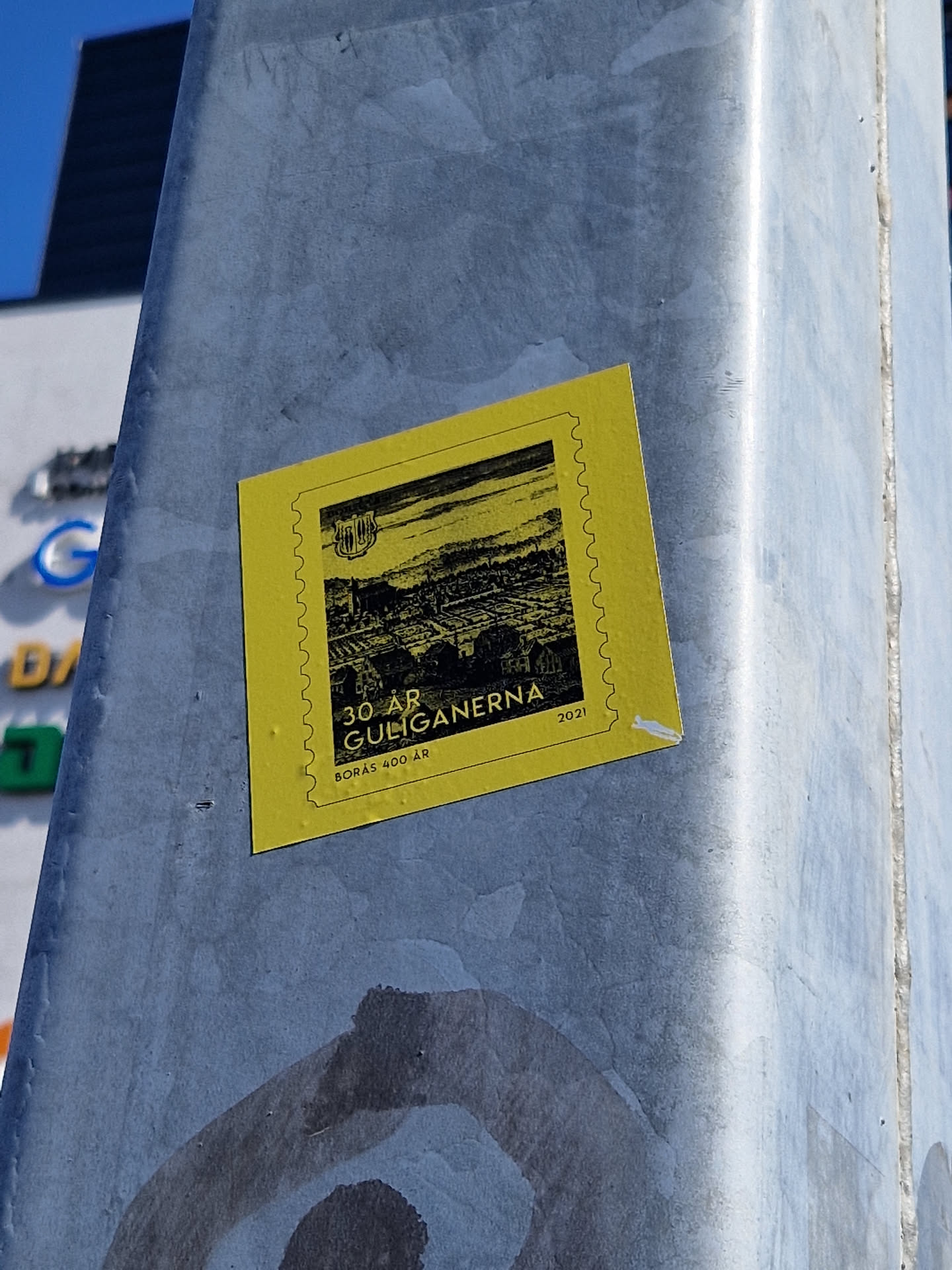 Yellow sticker commemorating 30 years of Gueiganerna. The sticker features a black and white illustration of a landscape.