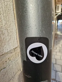 A black and white sticker with a heart shape and the text 'Above Love'.