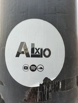 Round white sticker with the word Axio in a stylized font.  It includes links to the artist's YouTube, Spotify, and SoundCloud pages.