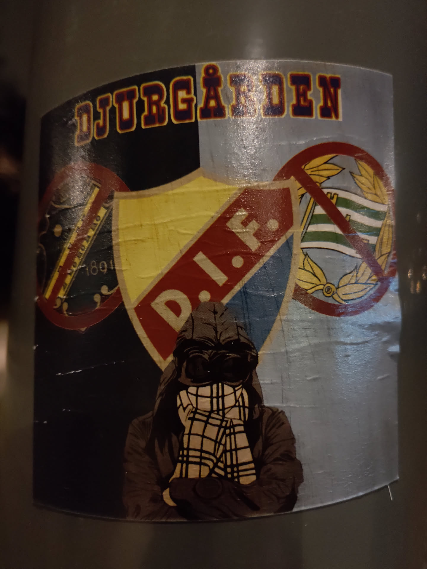 Sticker featuring an illustration of a person wearing a hoodie and a scarf, with the Djurgården IF logo and other design elements. 