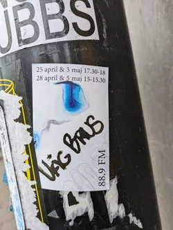 A sticker with an abstract blue and white design. It includes the text "Vag Brus" written in black marker, "88.9 FM" written vertically on the right side, and dates and times indicating two events: 25 april & 3 maj 17.30-18 and 28 april & 5 maj 15-15.30.