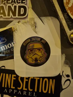 A sticker featuring a Stormtrooper helmet with floral tattoo designs. The sticker has the Instagram handle @sour_tattoo_art printed on it.