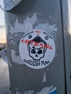 Round sticker featuring a skull graphic with the band name Käftsmäll and the words 'Swedish Punk'.  Social media links for Facebook and Spotify are also included.