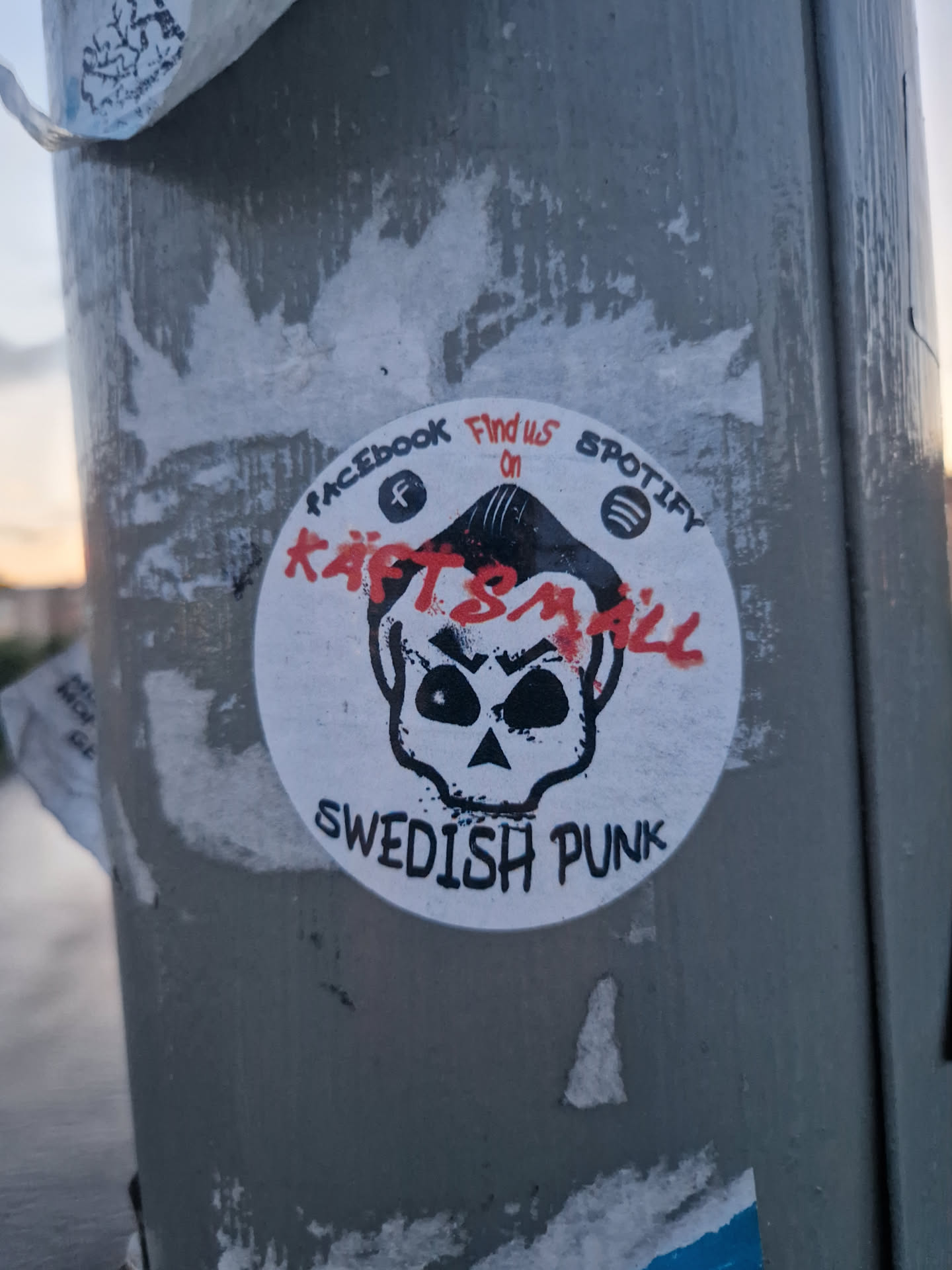 Round sticker featuring a skull graphic with the band name Käftsmäll and the words 'Swedish Punk'.  Social media links for Facebook and Spotify are also included.