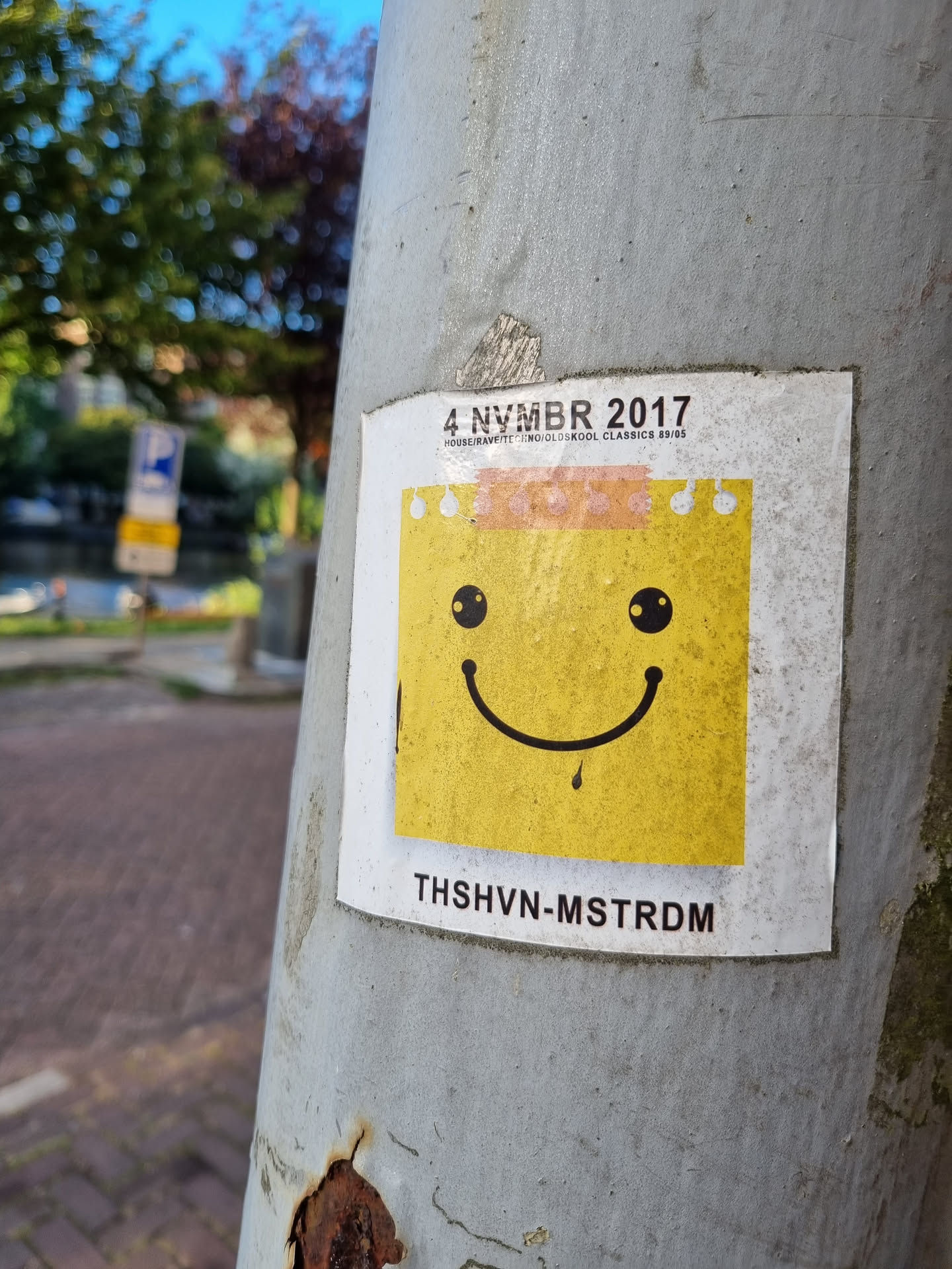 A yellow smiley face sticker with a dripping mouth, part of a series from 4 November 2017. The sticker has the text 'THSHVN-MSTRDM' at the bottom, possibly indicating the artist's location or name.