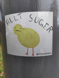 A sticker with a simple drawing of a bird and the text "All Sucks" written above it. The artist's Instagram account is mentioned in the bottom right corner.
