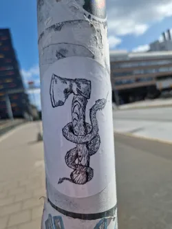 Black and white illustration of an axe with a snake wrapped around the handle. The sticker is slightly worn but the image is still visible.