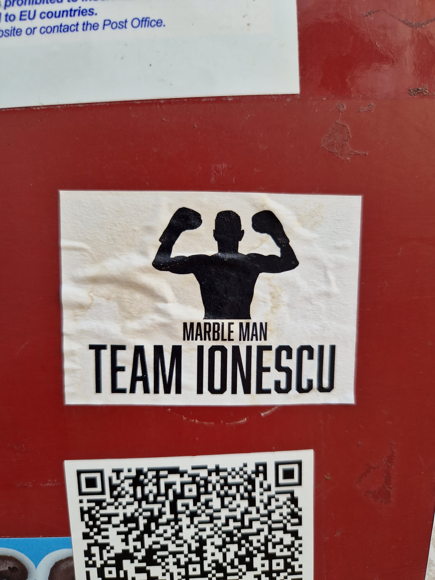 A sticker featuring a silhouette of a man flexing his biceps, with the text "Marble Man" and "Team Ionescu" below it.  A QR code is present below the main graphic.
