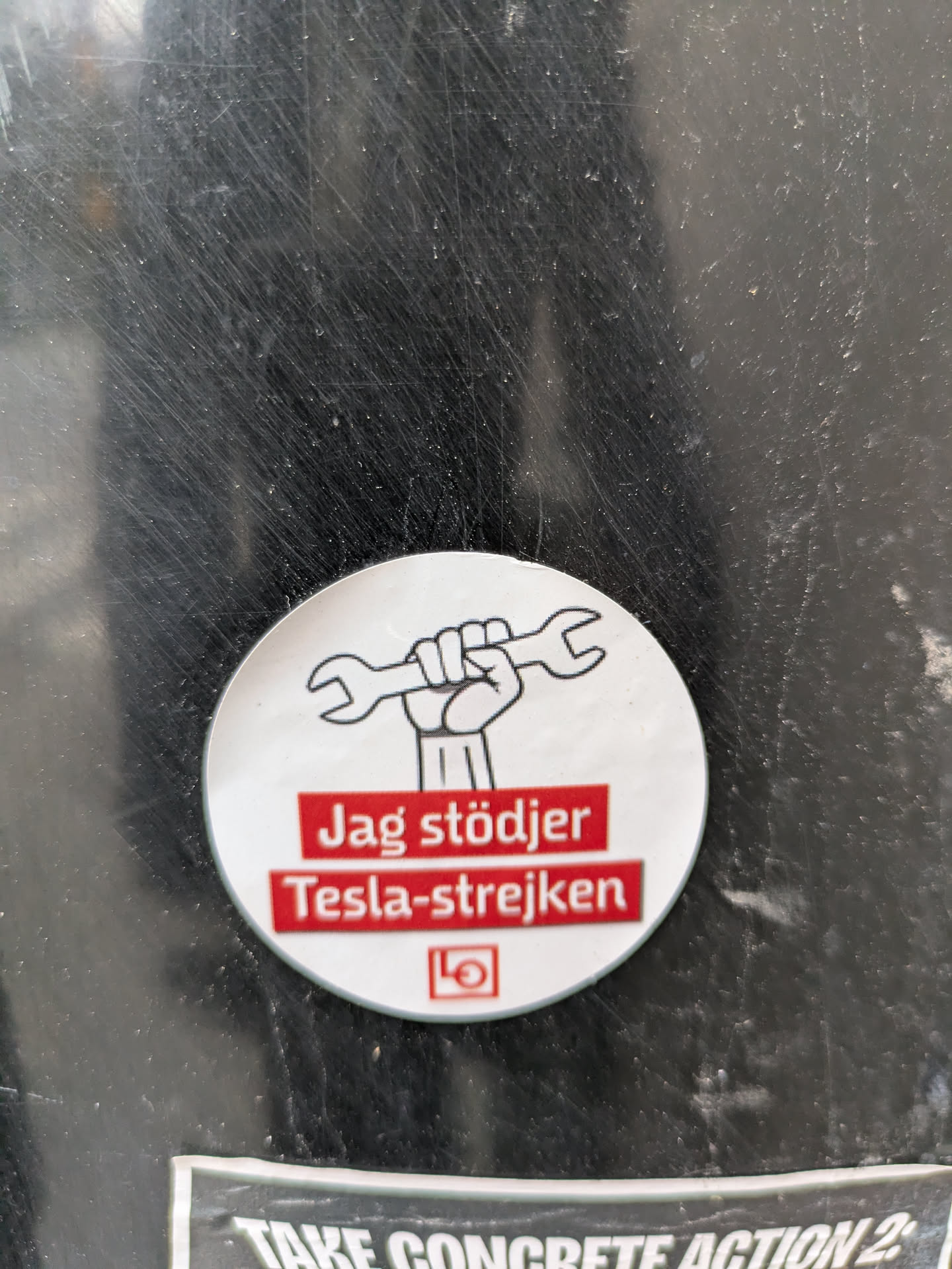 A round sticker expressing support for the Tesla strike. It features an illustration of a fist holding a wrench and the text "Jag stödjer Tesla-strejken" (I support the Tesla strike) in Swedish.
