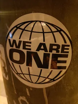 A round sticker with a globe and the text 'We Are One'.