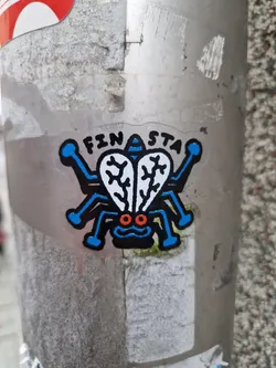 A sticker featuring a cartoon fly with blue legs and body, red eyes, and white wings. The word "FINASTA" is written above the fly.