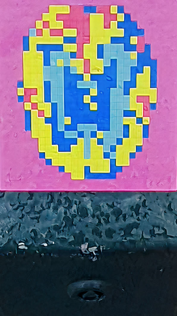 This is a pixelated sticker. It seems to be a colorful design of blue, yellow and pink shades on a pink wall. The sticker is made up of small squares, creating a blocky, pixelated effect. The placement is on what appears to be a pink painted surface.
