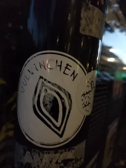 A black and white sticker with the word Vulinchen and a stylized leaf-like design.  The sticker is affixed to a dark pole.