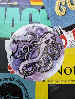 Round sticker featuring a watercolor-style illustration of an octopus. The octopus is drawn in black ink with purple watercolor washes in the background. The word "hautbild" is written in a small font at the top of the sticker.