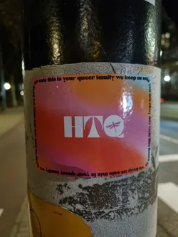 A sticker featuring the acronym HTO and a dragonfly graphic, with the message "This is your queer family. We keep us safe." It has a gradient background of pink and orange.