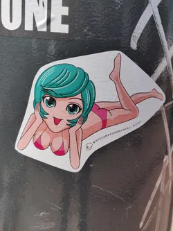 A sticker featuring an illustration of a girl with teal hair, lying down and wearing a pink bikini. The art style is reminiscent of anime or manga. The sticker is white with a slightly rounded edge. A small logo or watermark is present at the bottom right corner, alongside the artist's handle and year of creation. 