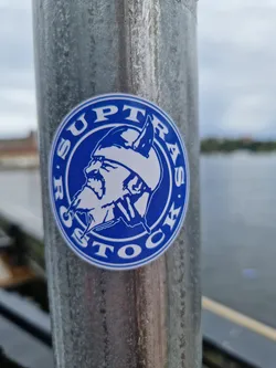 A blue and white circular sticker featuring a Viking's head design. The text 'Suptrass Stock' is written around the circle. 