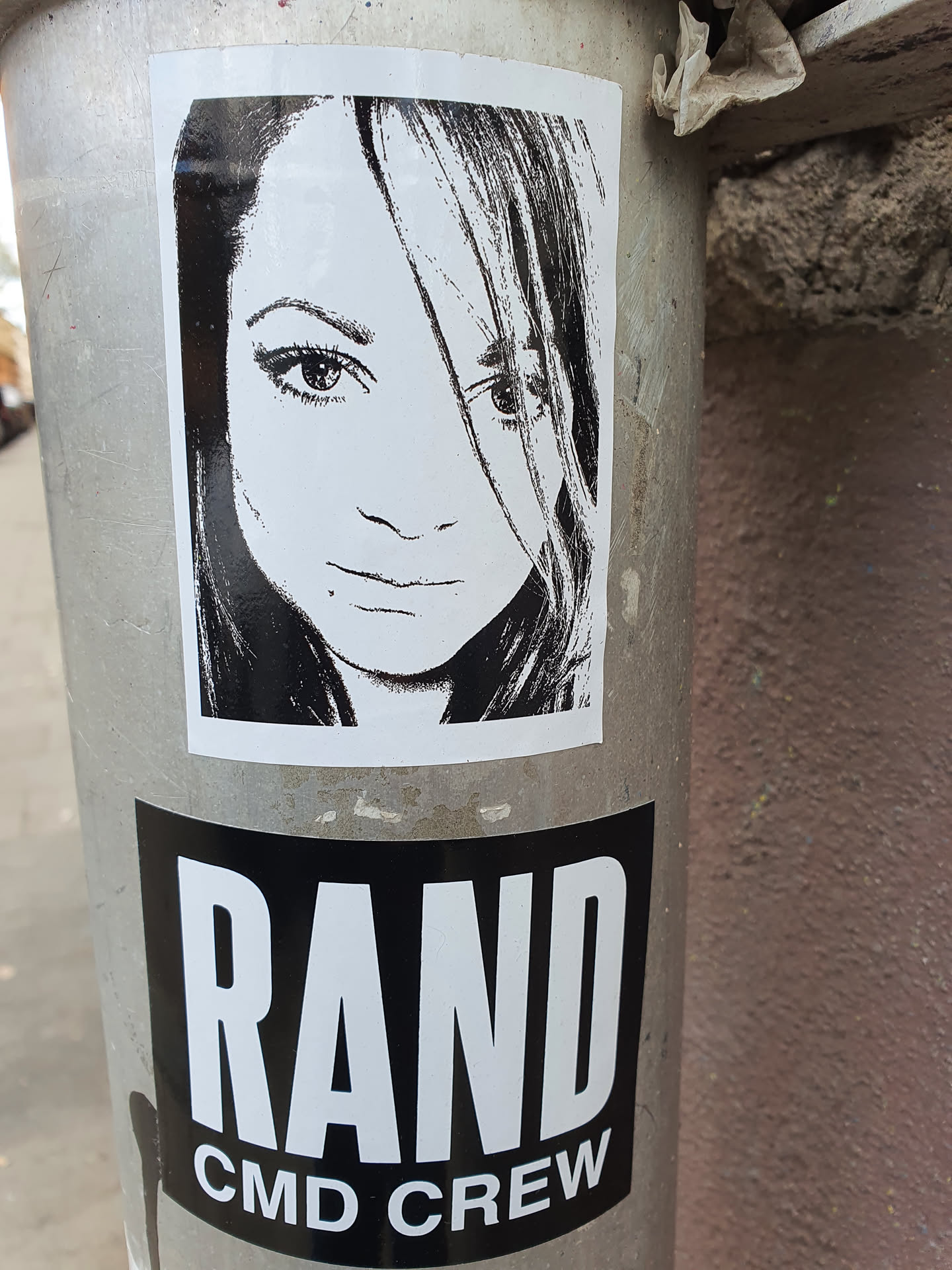 A black and white sticker featuring a portrait of a woman.  Below the portrait is a second sticker with the text "RAND CMD CREW".
