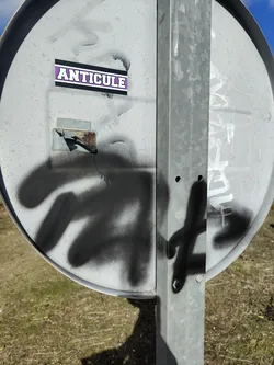 Street sticker A rectangular sticker featuring the word "ANTICULE" in prominent, bold, white block letters with a thin black outline. The letters are set against a vibrant purple background, which is then framed by a thicker black border. The sticker is applied to a weathered, grey metal surface, which shows signs of wear, spray paint, and some rust.