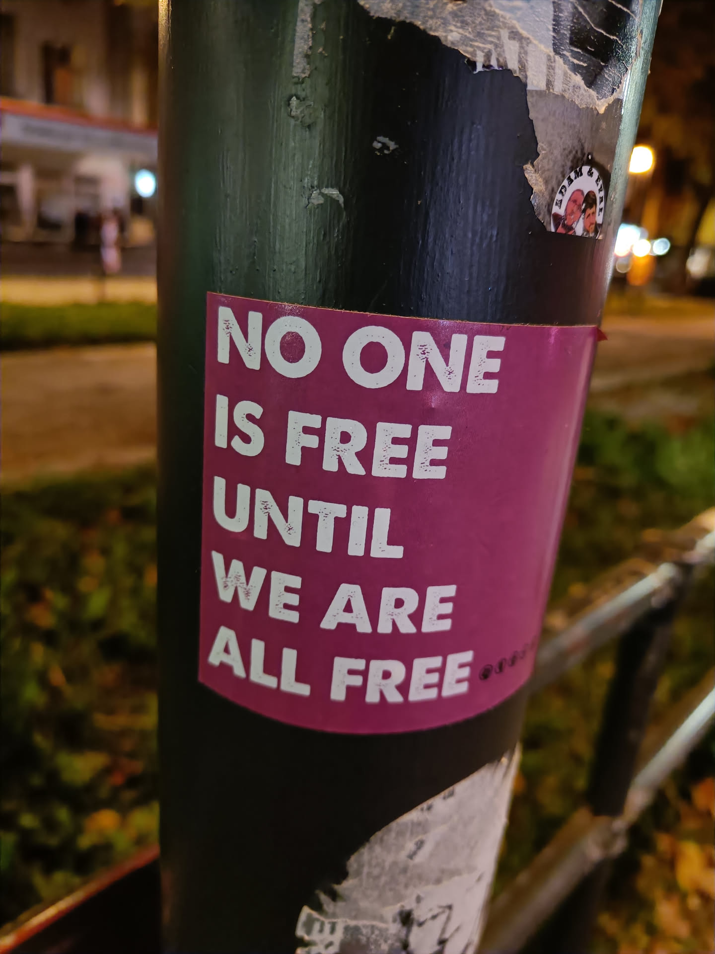 A sticker with a powerful message about freedom and equality.  The sticker is affixed to a dark pole, suggesting it may be part of a street art or activist campaign.