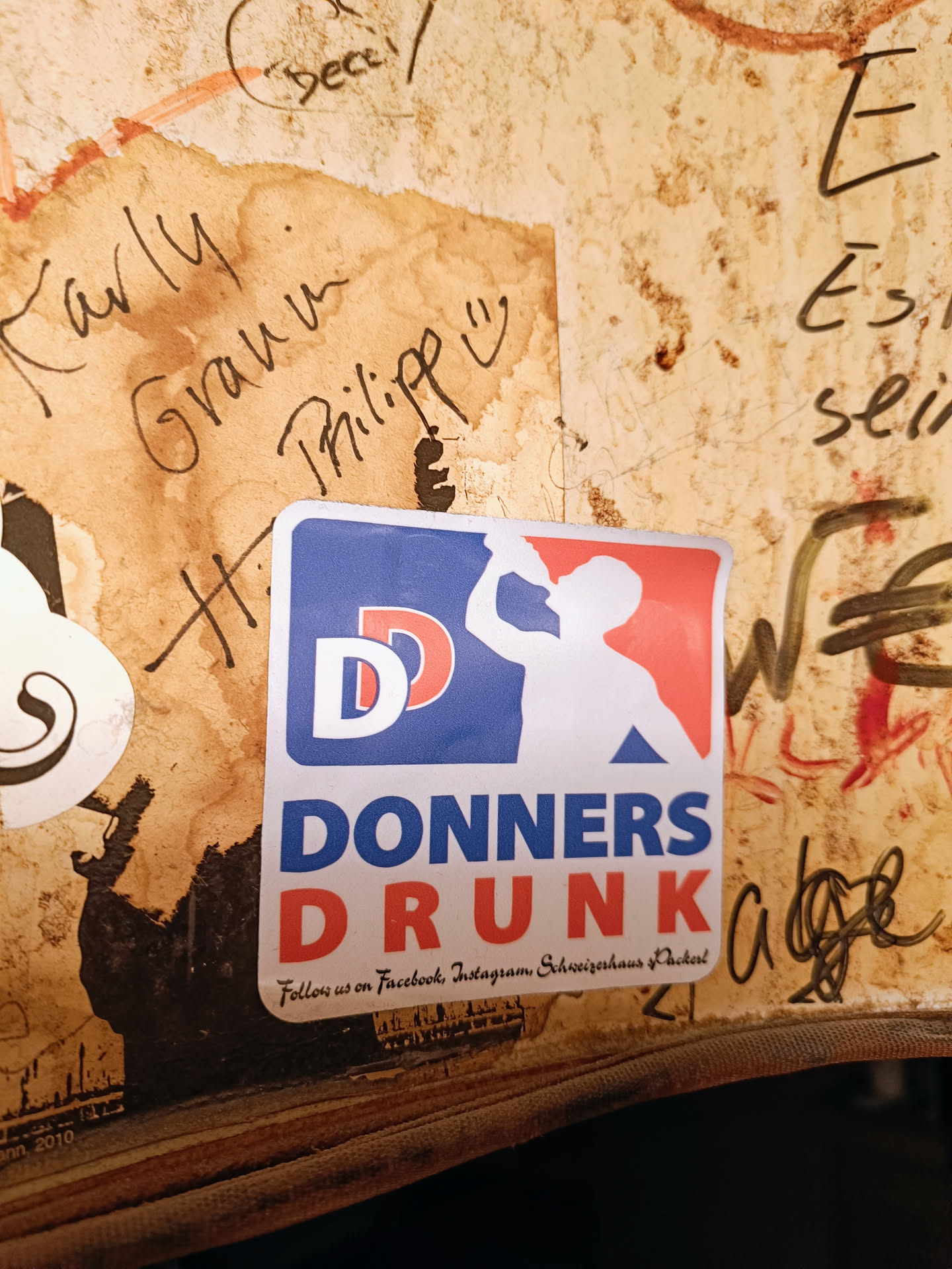 A sticker with a logo and text. The logo is a baseball-style graphic with the letters 'DD' and an illustration of a person drinking. The text reads 'DONNERS DRUNK' and includes instructions to follow on Facebook and Instagram.