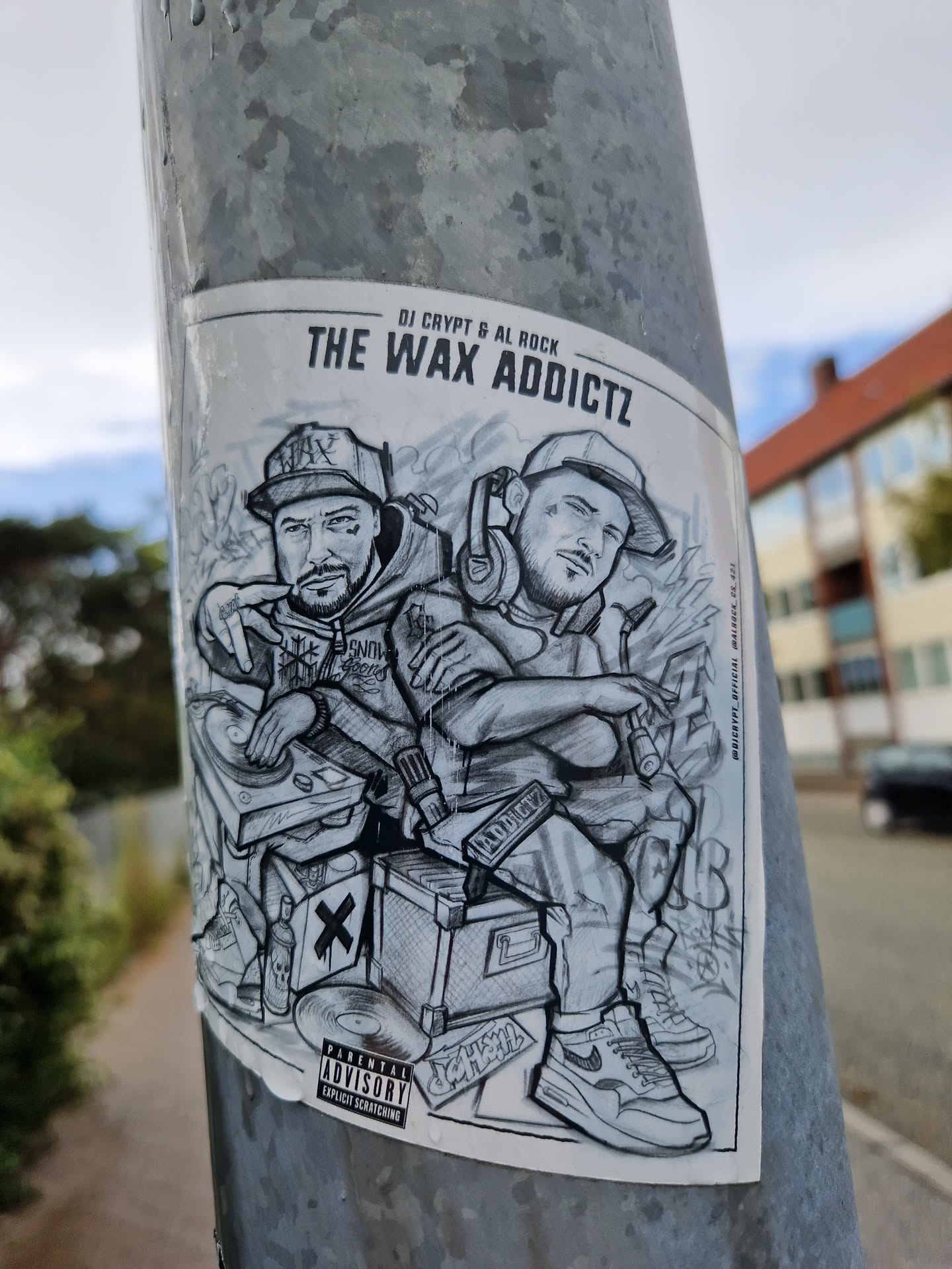 A grayscale sticker featuring an illustration of two DJs, DJ Crypt and Al Rock, with their equipment.  The style is reminiscent of graffiti or street art.  It includes a parental advisory label.