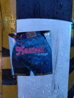 A sticker featuring a pair of vintage jeans. The sticker is wet from the rain.  The text on the sticker says "Mazzel vintage" and includes a website address.