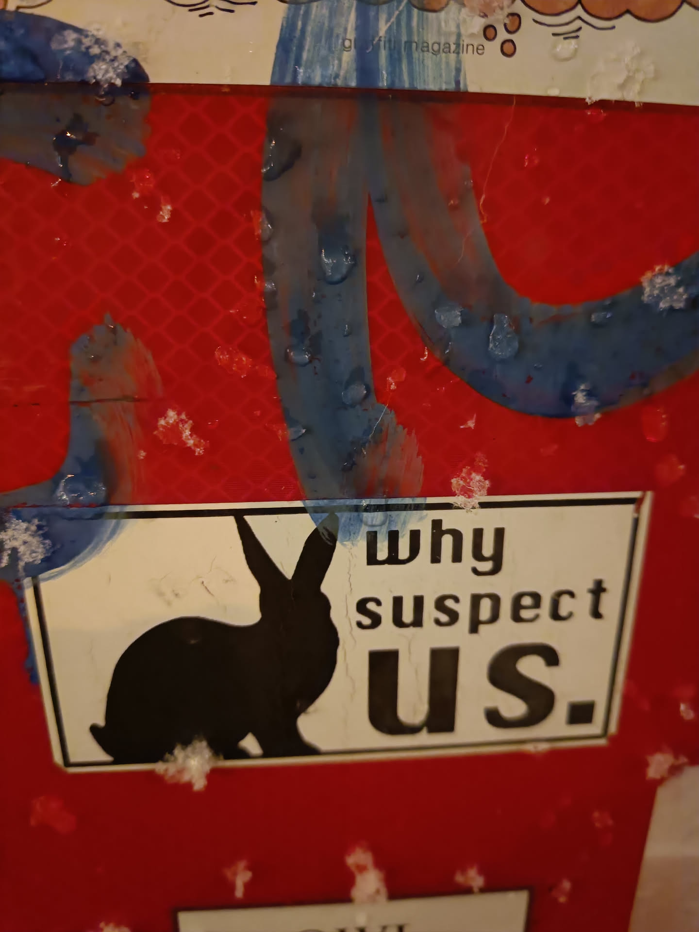 A black and white sticker featuring a silhouette of a rabbit and the text 'Why suspect us.' The sticker is affixed to a red surface.