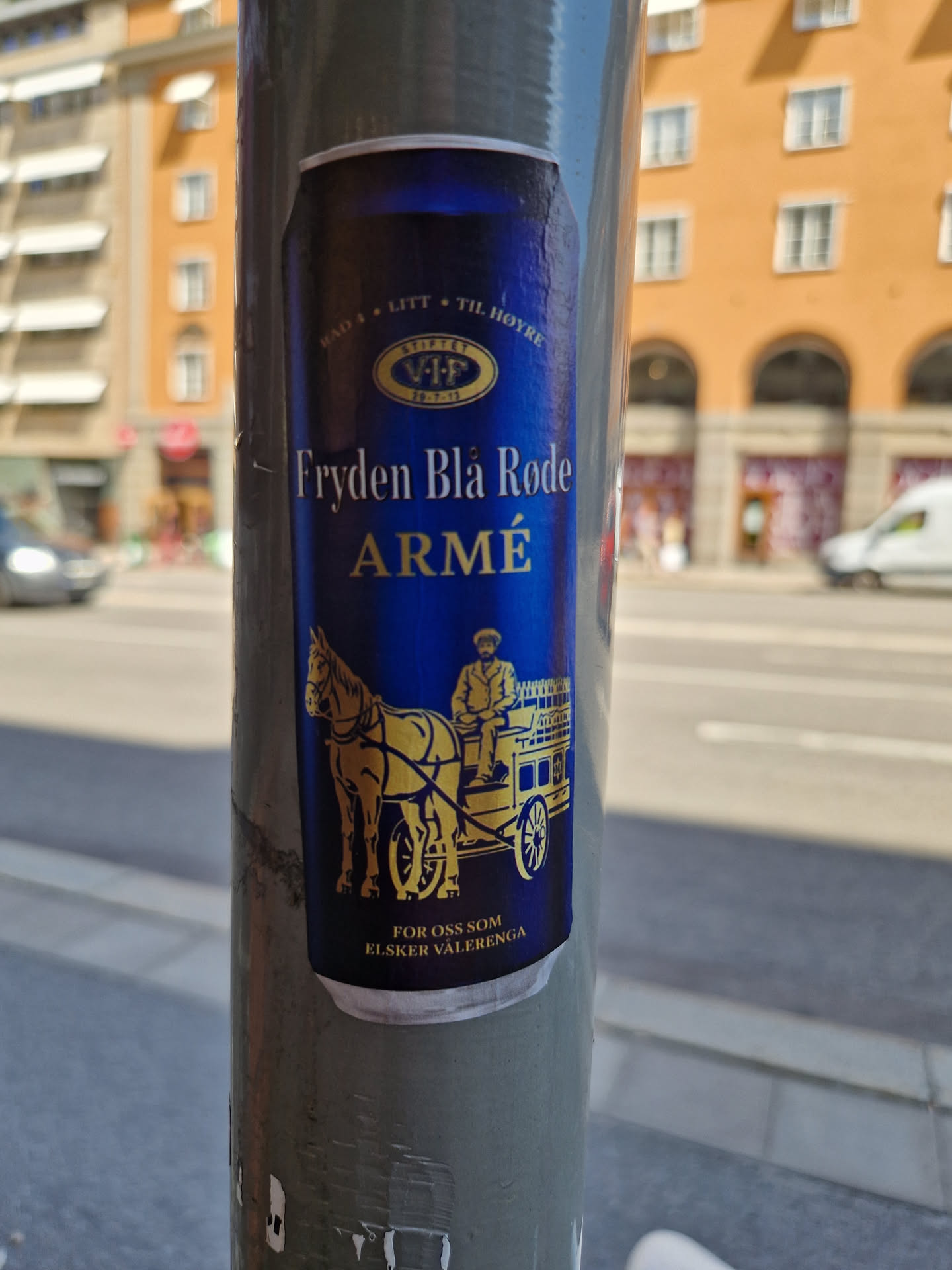 A sticker featuring a design reminiscent of a beer can label.  The central image shows a horse-drawn carriage with a person in a driver's seat. The text 'Fryden Blå Røde Armé' is prominently displayed, along with smaller text at the top and bottom. The overall color scheme is dark blue and gold.