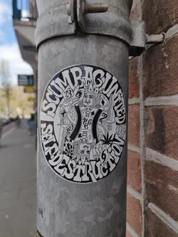 A round sticker with a design featuring a king figure in the center surrounded by text that reads "SCUMRAGUNTIED SELFDESTRUCTION." The king is depicted with playing cards and other symbolic imagery.