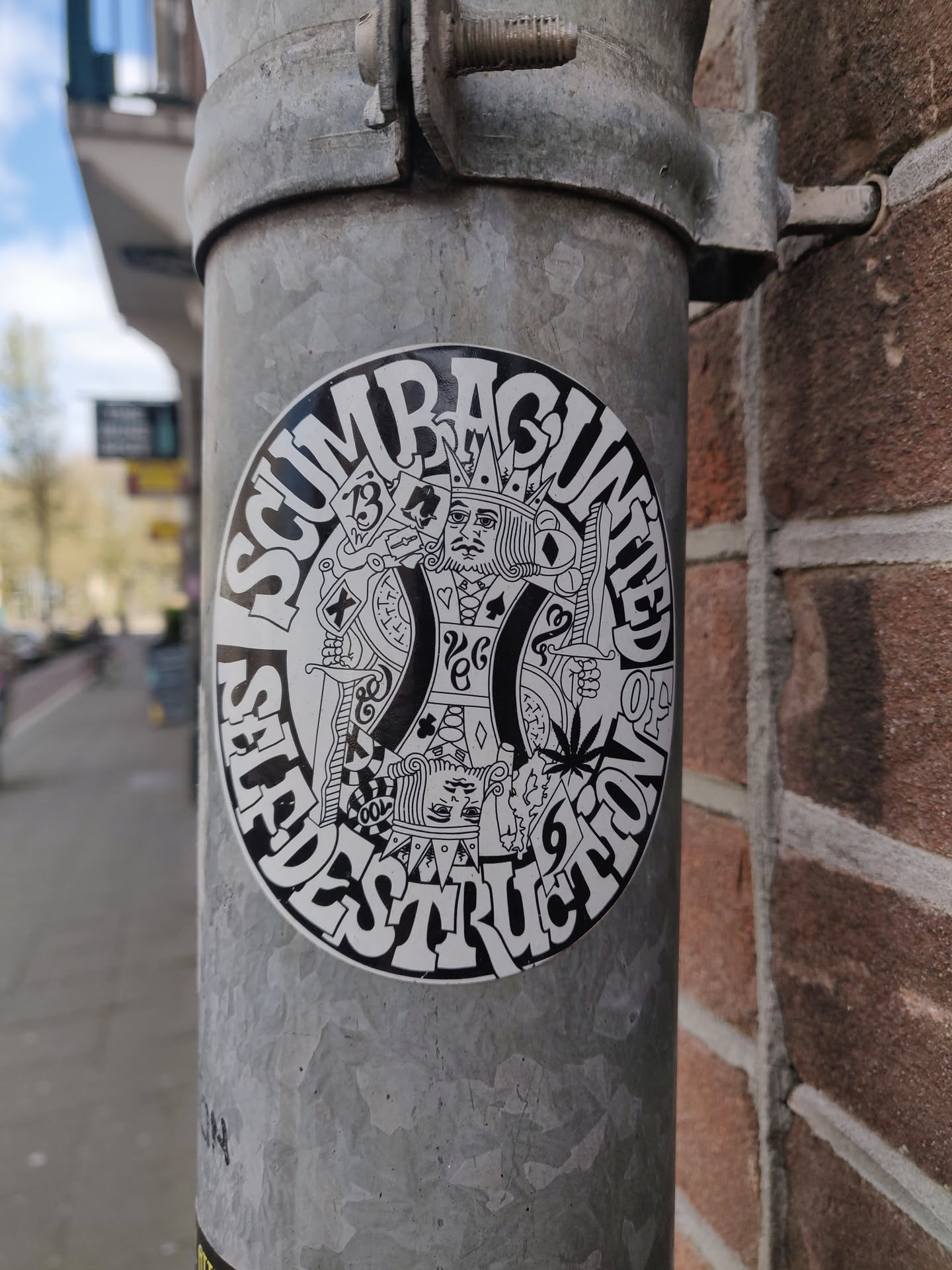 A round sticker with a design featuring a king figure in the center surrounded by text that reads "SCUMRAGUNTIED SELFDESTRUCTION." The king is depicted with playing cards and other symbolic imagery.