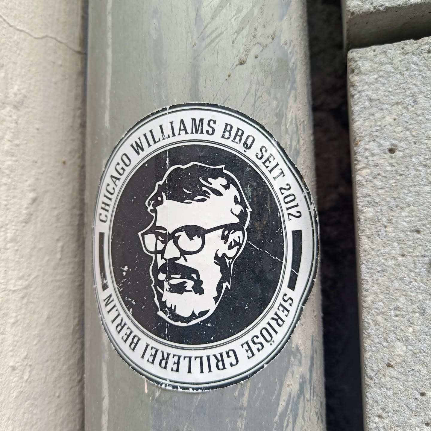A black and white sticker featuring a portrait of a man with glasses and a beard. The text around the portrait reads "Chicago Williams BBQ Seit 2012" and "Seriöse Grillerei Berlin".