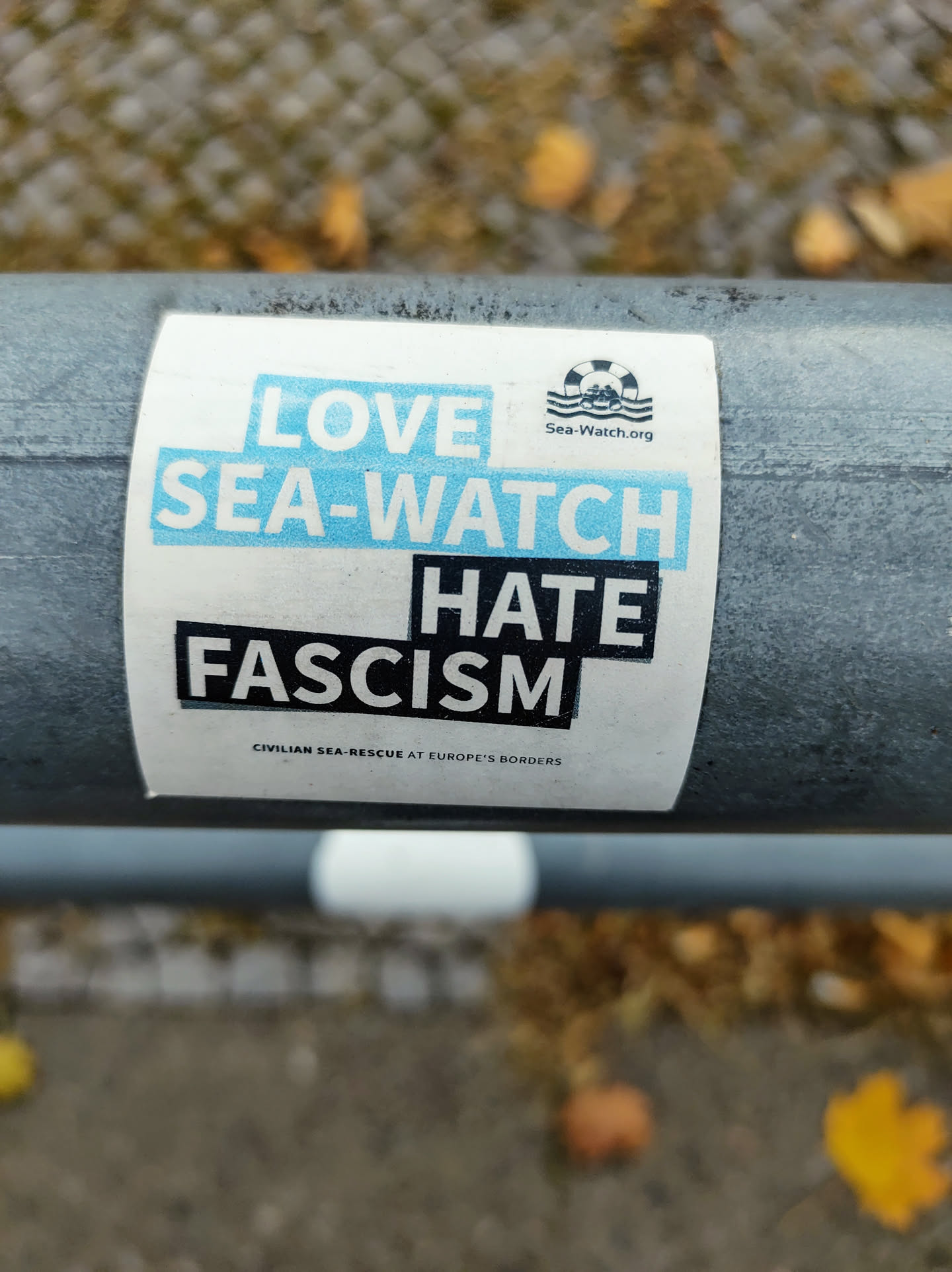 A sticker expressing support for Sea-Watch, an organization conducting civilian sea rescue at Europe's borders, and opposition to fascism. The sticker features the Sea-Watch logo and the text: "LOVE SEA-WATCH HATE FASCISM".