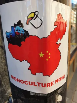 A sticker depicting a map of China being painted red with a bucket of paint, and a line of masked figures. The text 'Monoculture Now!' is at the bottom.