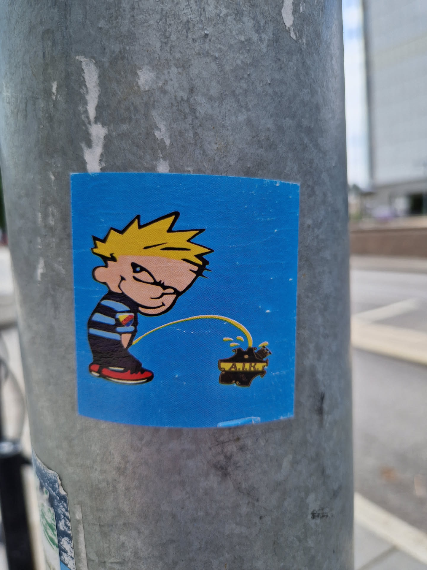 A sticker featuring Calvin from the comic strip Calvin and Hobbes, in a playful act of urinating on a logo that says "AIR". The sticker has a blue background and a cartoonish style.