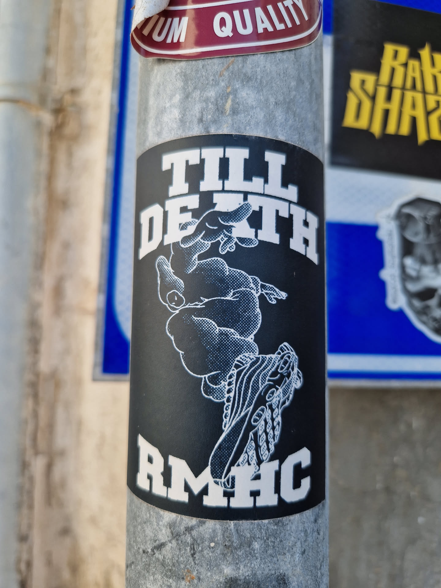 Black and white sticker with a graphic of a person falling and the text 'Till Death' above and 'RMHC' below. The style is reminiscent of streetwear or skate culture.