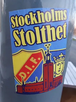 A sticker featuring the text "Stockholms Stolthet" (Stockholm's Pride) in yellow on a blue background. It includes imagery of Djurgårdens IF (DIF) football club logo, Stockholm City Hall, and a crowned figure. The design is reminiscent of vintage or retro style.