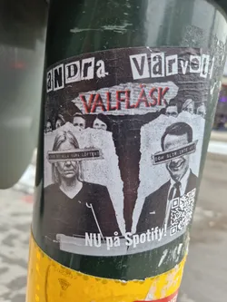 A sticker featuring a stylized image of two individuals, possibly politicians, with text obscuring their eyes. The text 'Andra Varvet' and 'Valflask' is prominently displayed, along with a Spotify promotion.  The design is somewhat collage-like with a ripped paper effect.