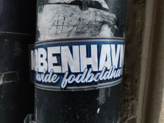 A sticker featuring the text "KØBENHAVN hvide fodboldhuer" in white lettering on a dark blue background. The text is stylized with a bold font and a curved script for the words "hvide fodboldhuer".
