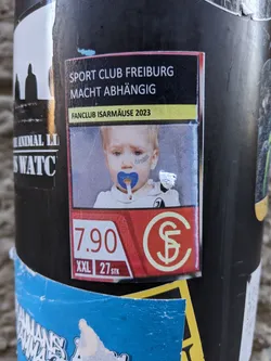 Sticker featuring a baby smoking a pacifier with the text 'Sport Club Freiburg macht abhängig' (Sport Club Freiburg makes you addicted) and 'Fanclub Isarmäuse 2023'.  The sticker also displays a price of 7.90, size XXL, and a quantity of 27.