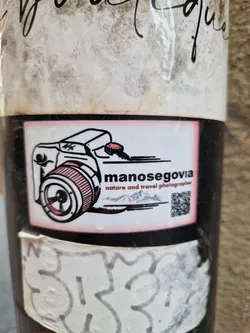 Sticker featuring a drawing of a camera, mountains, and a QR code. The text manosegovia nature and travel photographer is visible. 
