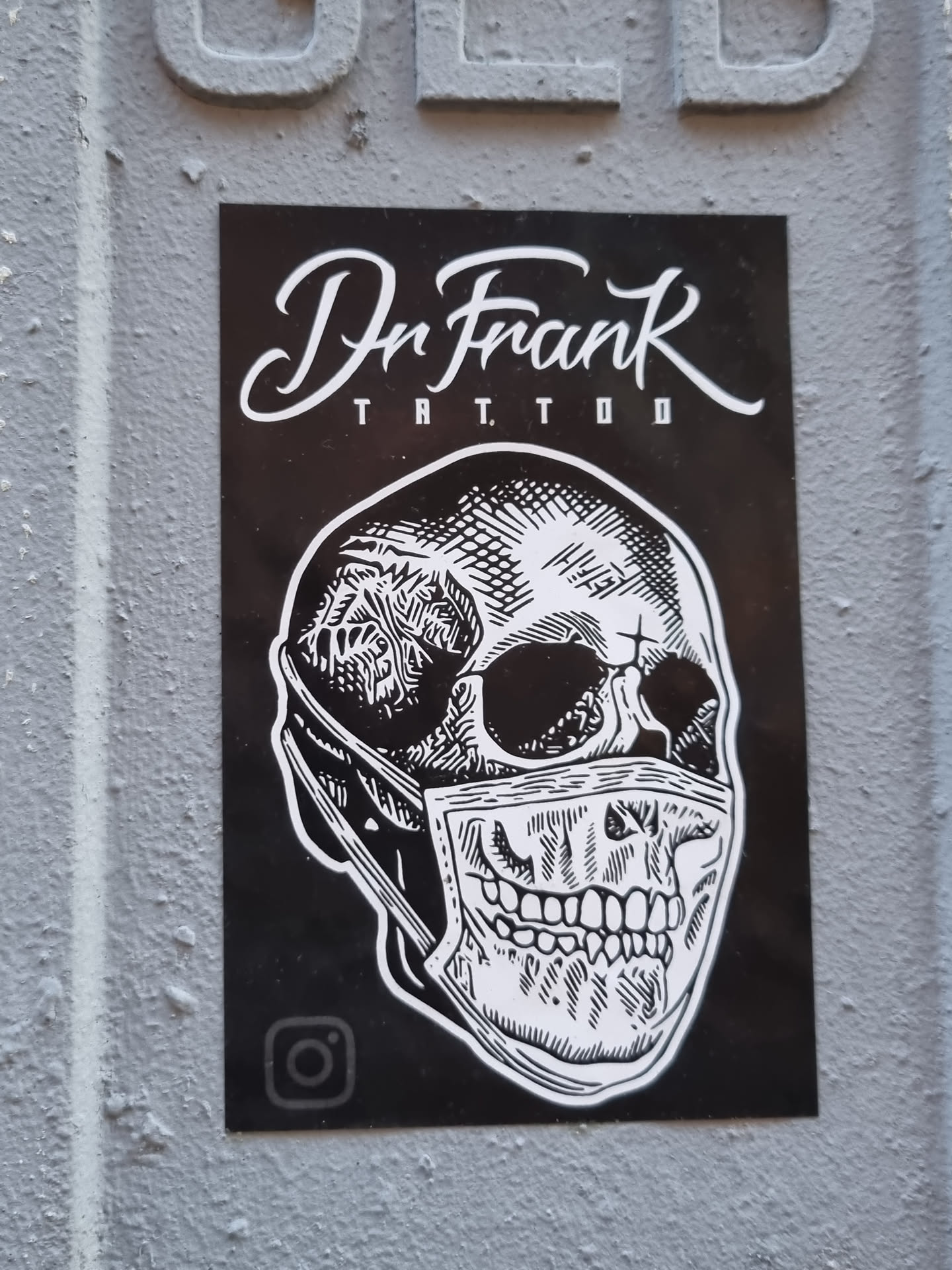 Black and white sticker featuring a skull wearing a facemask. The sticker has Dr. Frank Tattoo written at the top and an Instagram logo at the bottom.