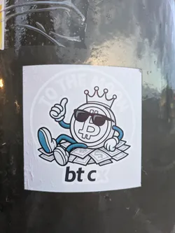 The sticker features a cartoonish illustration of a Bitcoin coin wearing sunglasses and a crown, sitting atop a pile of US dollar bills. The coin has arms and legs, with one arm giving a thumbs-up gesture. The overall color scheme is black, white, and blue, with dollar bills depicted in gray and white. The background of the sticker has a circular, faded text that reads "TO THE MOON."