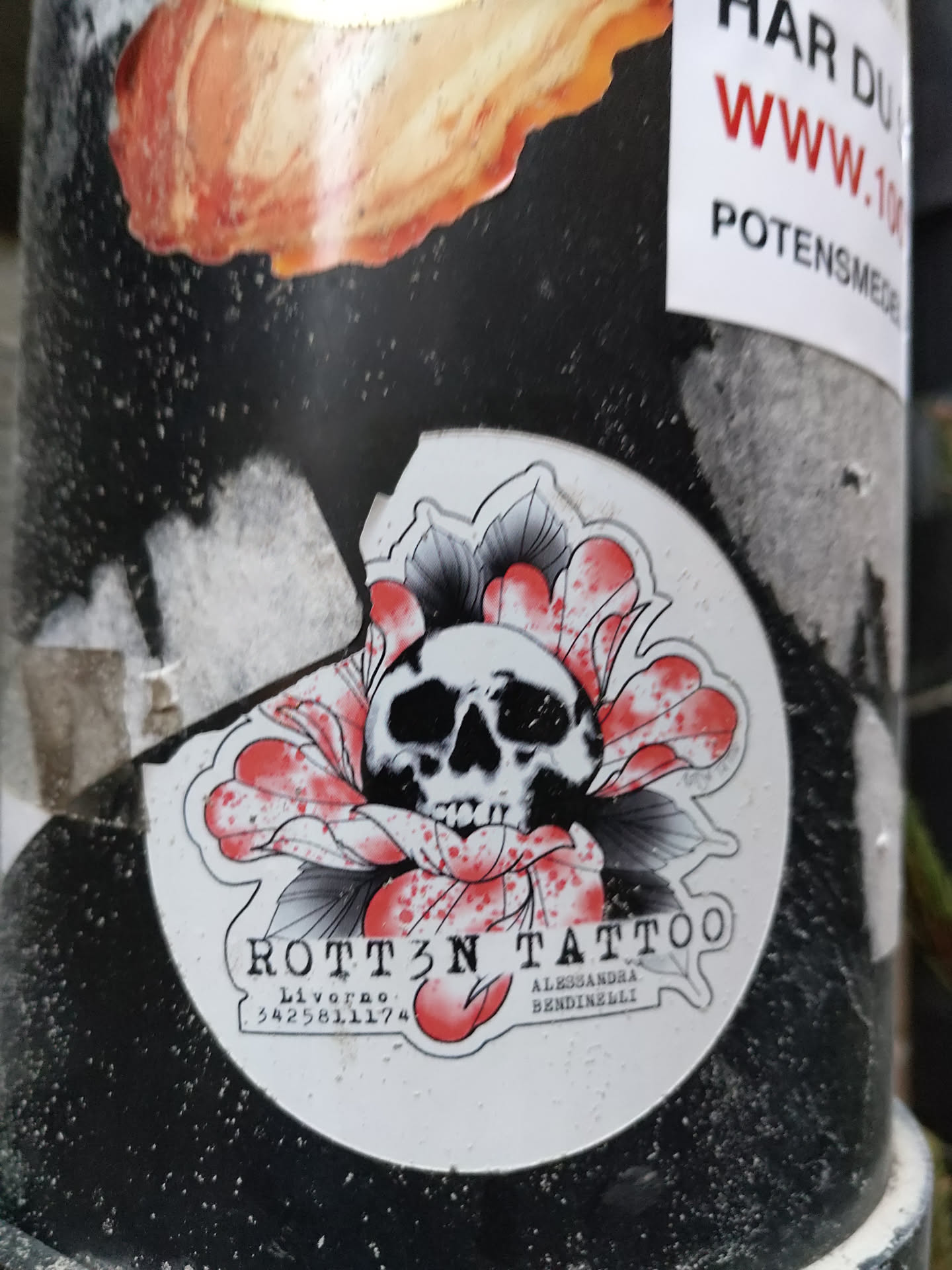 A round sticker featuring a black and white skull nestled within a red flower. The sticker has the text 'ROTT3N TATTOO', 'Livorno', 'Alessandra Bendinelli', and a phone number.