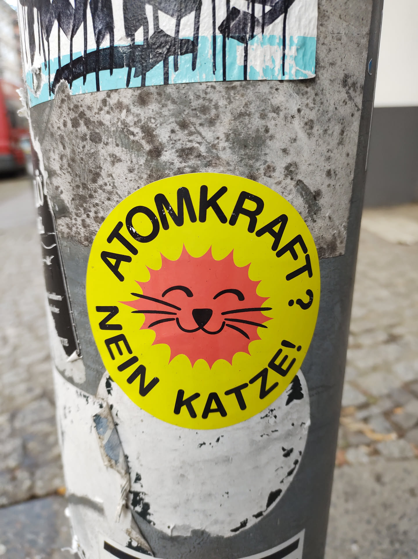 A round yellow sticker with a cute cartoon cat and the German text "Nein Atomkraft Katze!" which translates to "No nuclear power cat!"