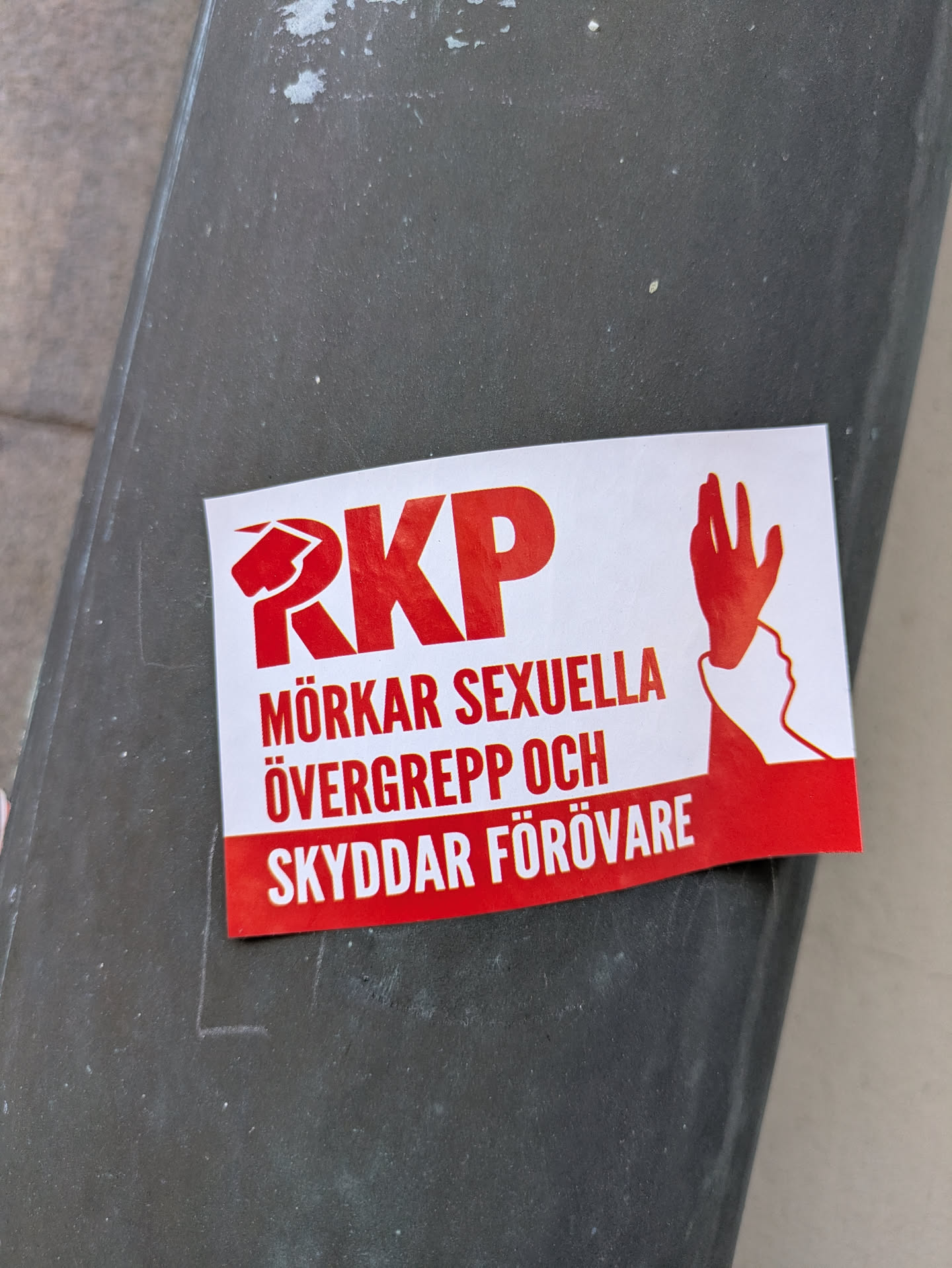 The sticker is red and white and features the text "RKP MÖRKAR SEXUELLA ÖVERGREPP OCH SKYDDAR FÖRÖVARE" along with a logo of RKP and a graphic of a hand silencing a face.